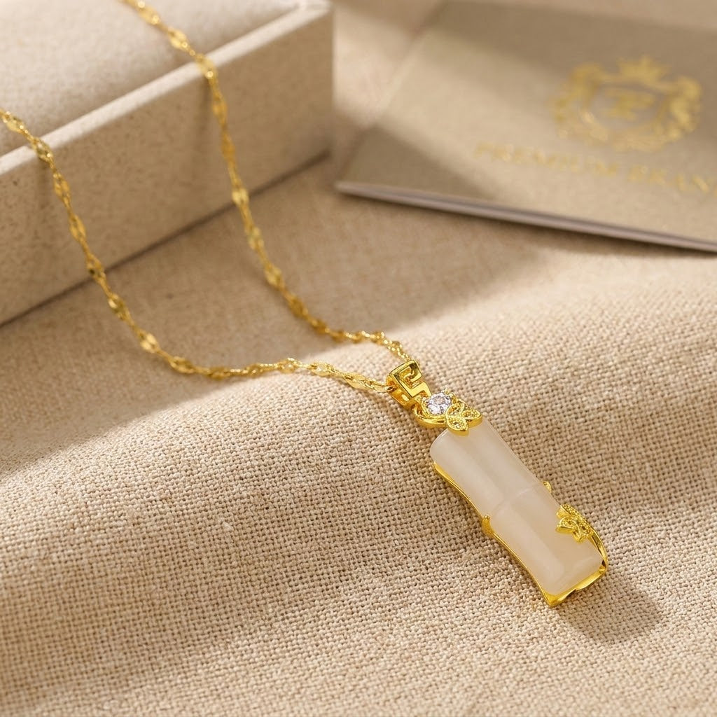 Gold necklace with pale pink segmented pendant on textured fabric with thin chain