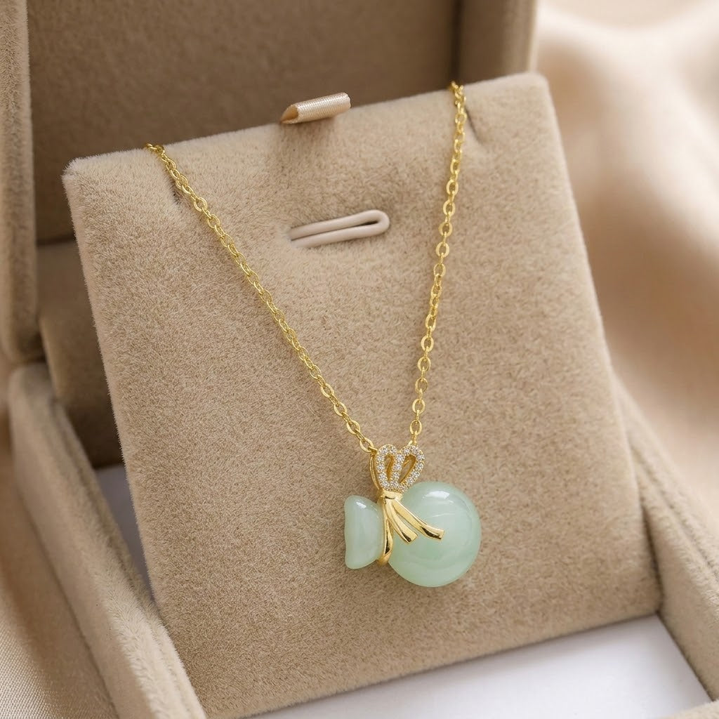 Gold-tone necklace with crown charm and light aqua bead pendant with bow details