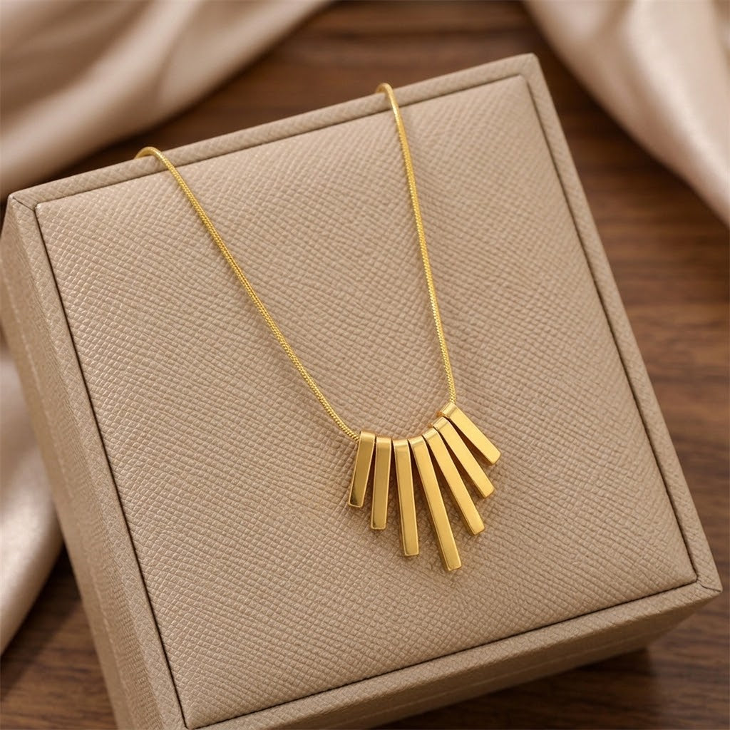 Gold-tone fringe feather pendant necklace displayed on a gift box