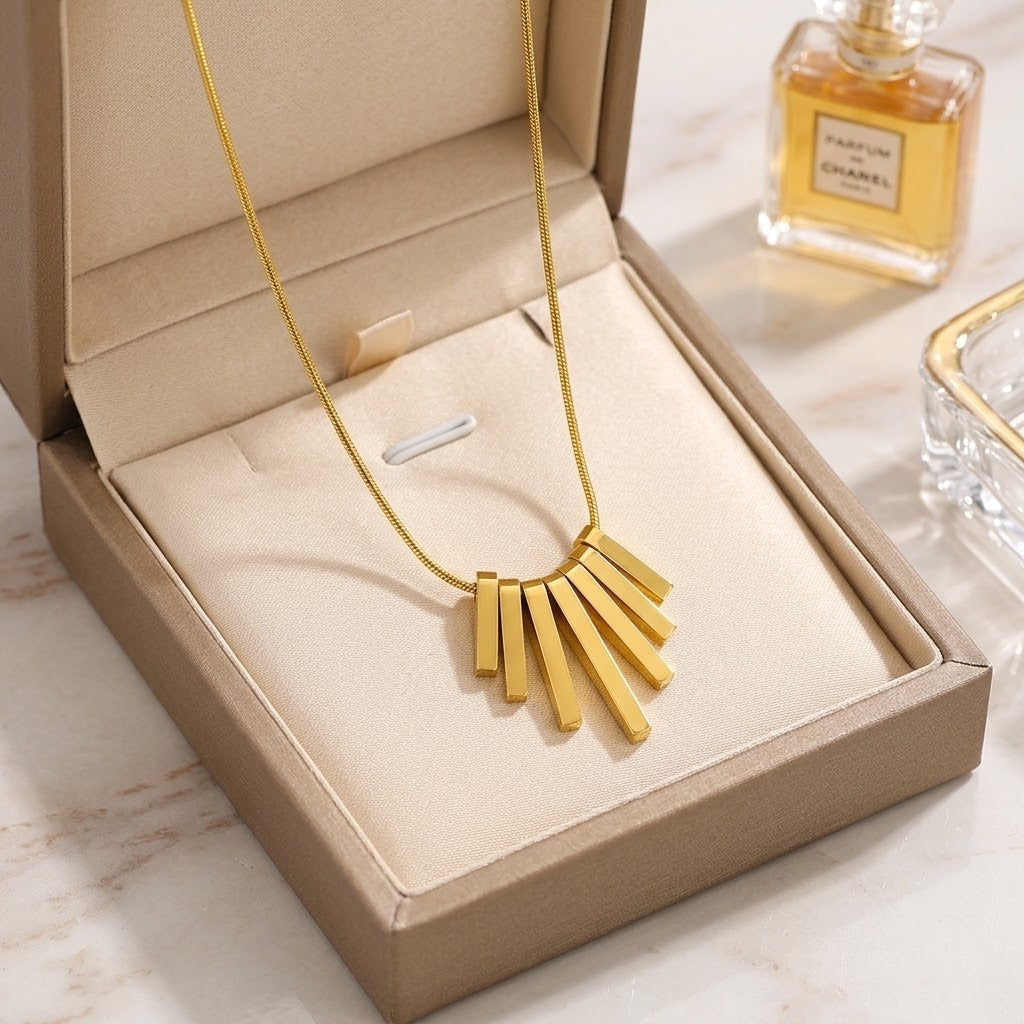 Gold-tone fringe charm necklace in a jewelry box on a slim chain