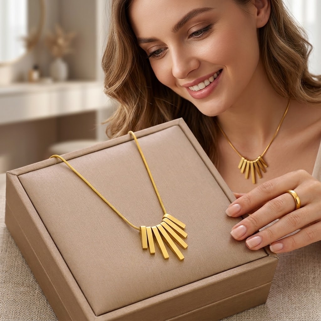 Gold-tone fringe feather pendant necklace worn with a gift box