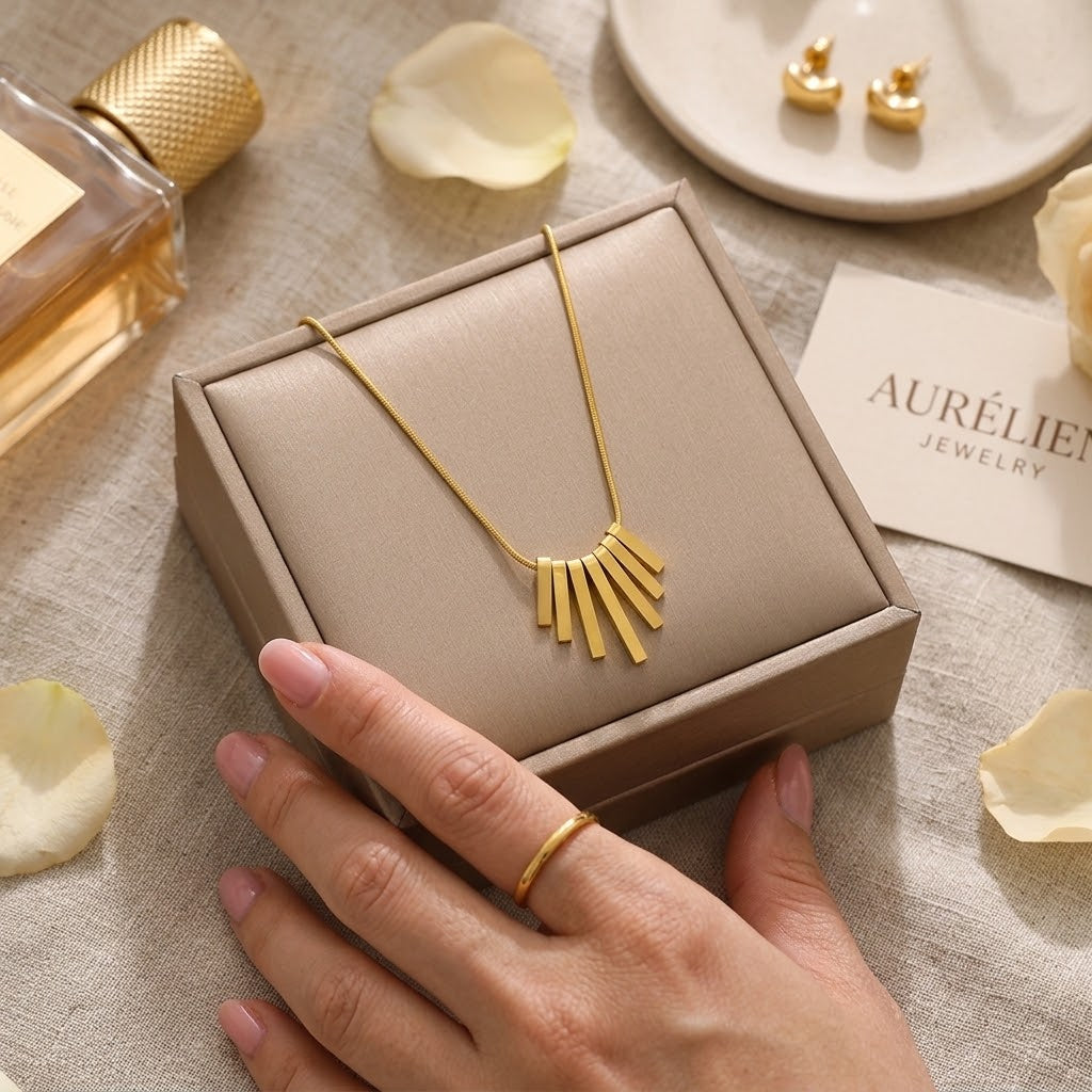 Gold-tone fringe feather pendant necklace in a jewelry box, held in hands