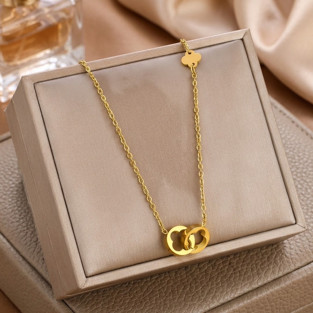 Gold-tone clover pendant necklace with chain, displayed in a jewelry box