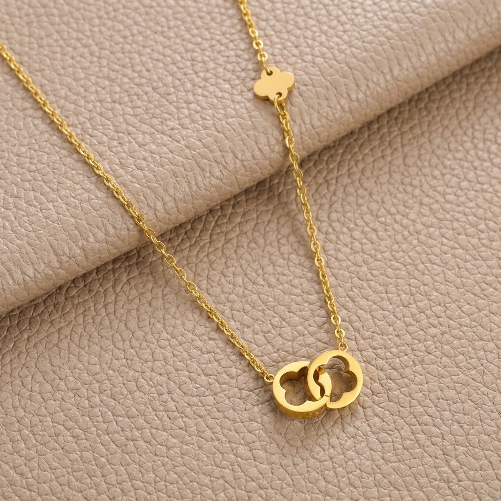 Gold-tone clover pendant necklace with chain on light leather surface