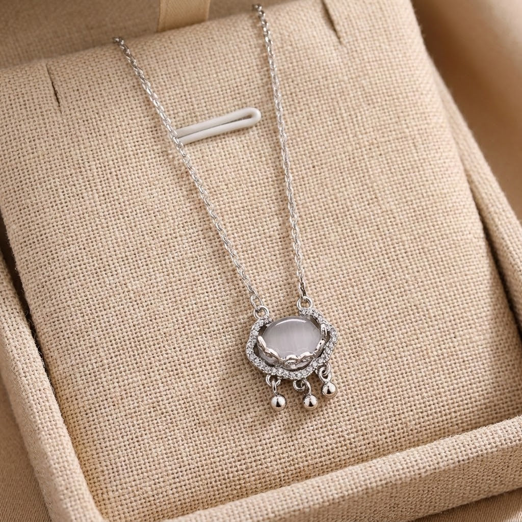 Silver-tone oval halo charm necklace with crystal ring and small bead drops