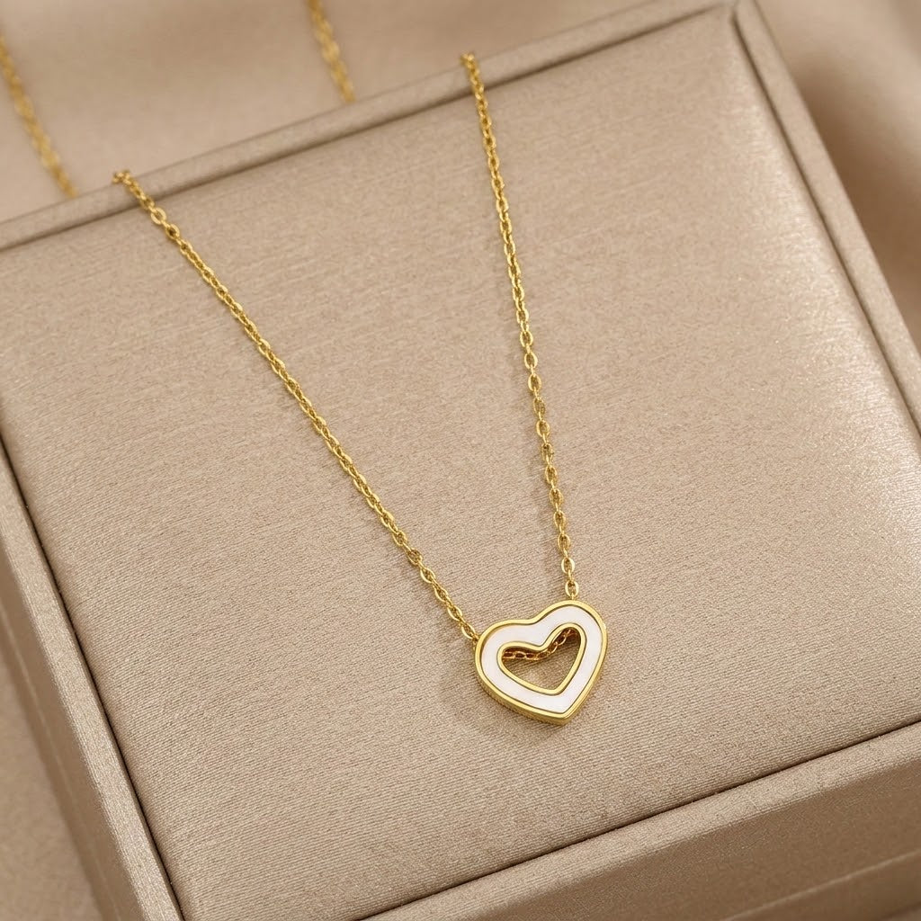 Gold-tone hollow heart pendant necklace on a chain, close-up in jewelry box