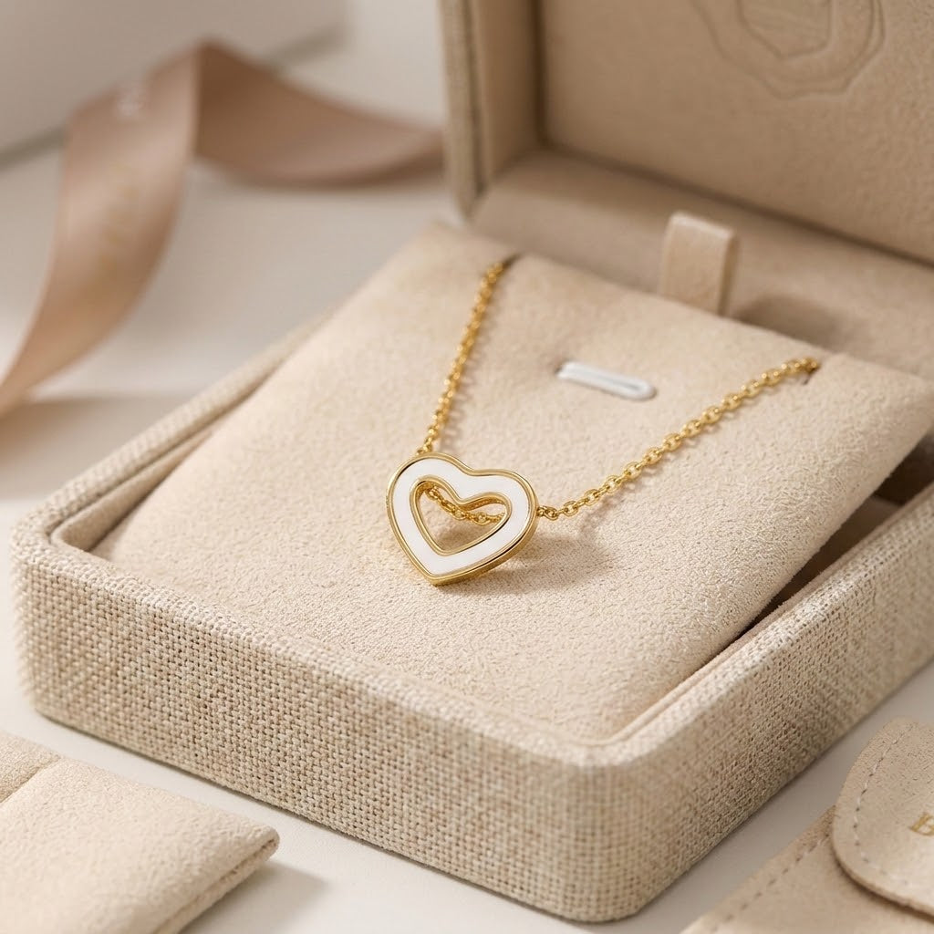 Gold-tone hollow heart pendant necklace resting in beige jewelry display box