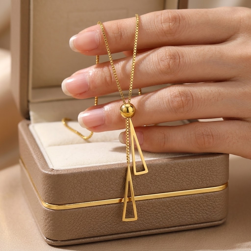 Gold double triangle charm necklace with two dangling triangle charms on hand