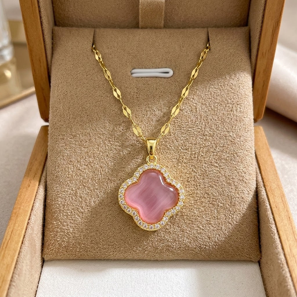 Gold clover pendant necklace with pink-purple enamel center and stone halo