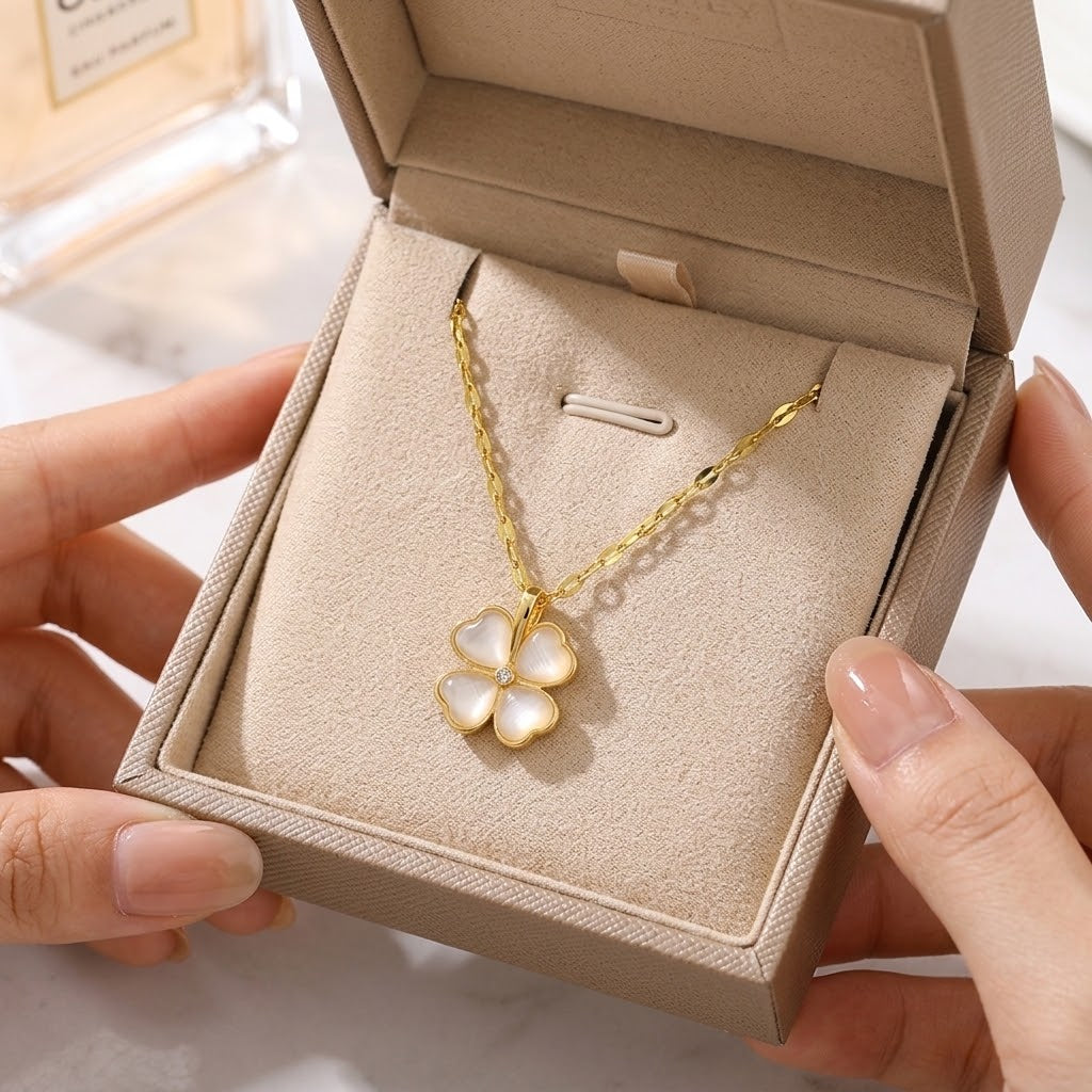 Gold four-petal flower pendant necklace in an open jewelry box