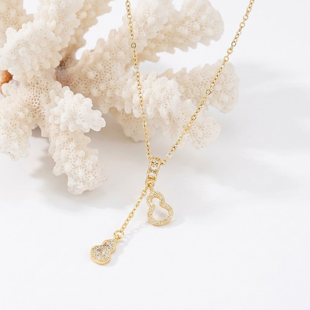 Gold-tone heart charm necklace with center teardrop pendant and two dangling heart charms