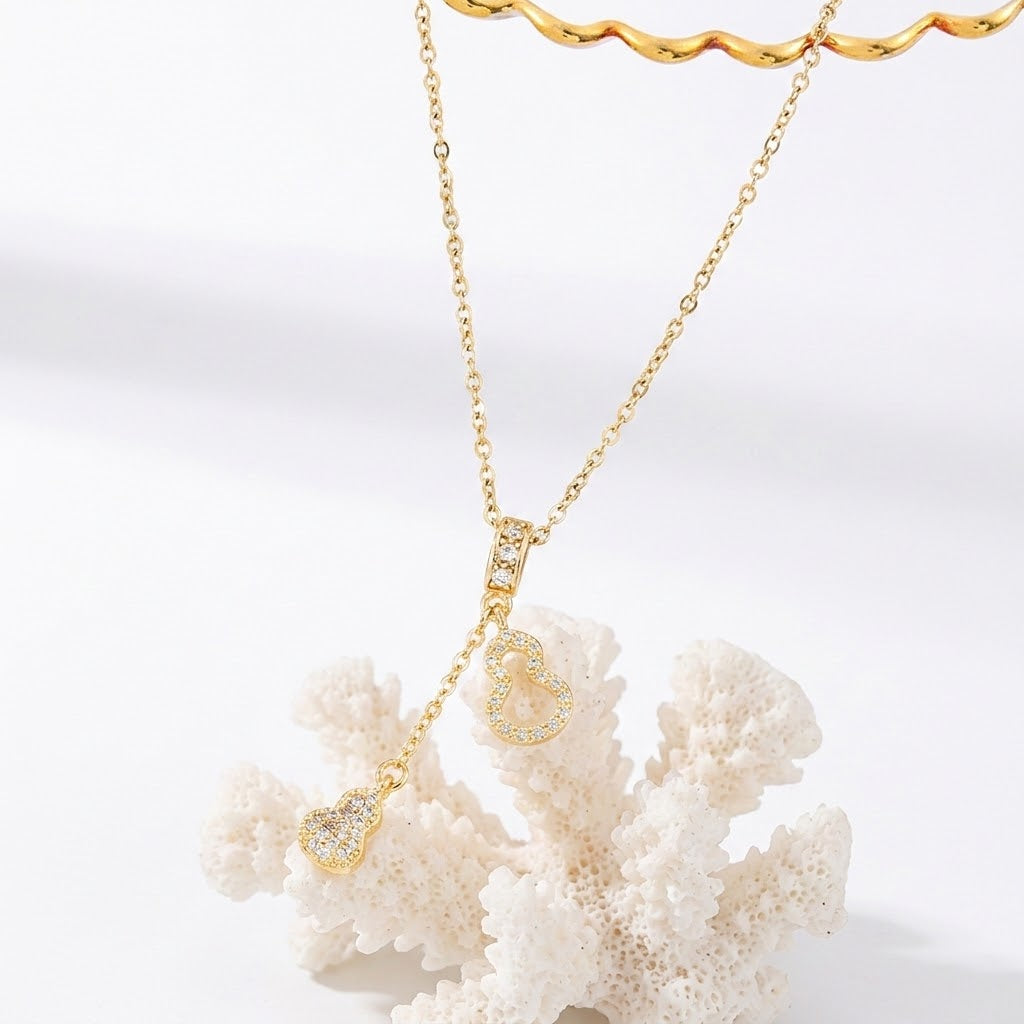Gold-tone heart charm necklace featuring three dangling charms on a delicate chain