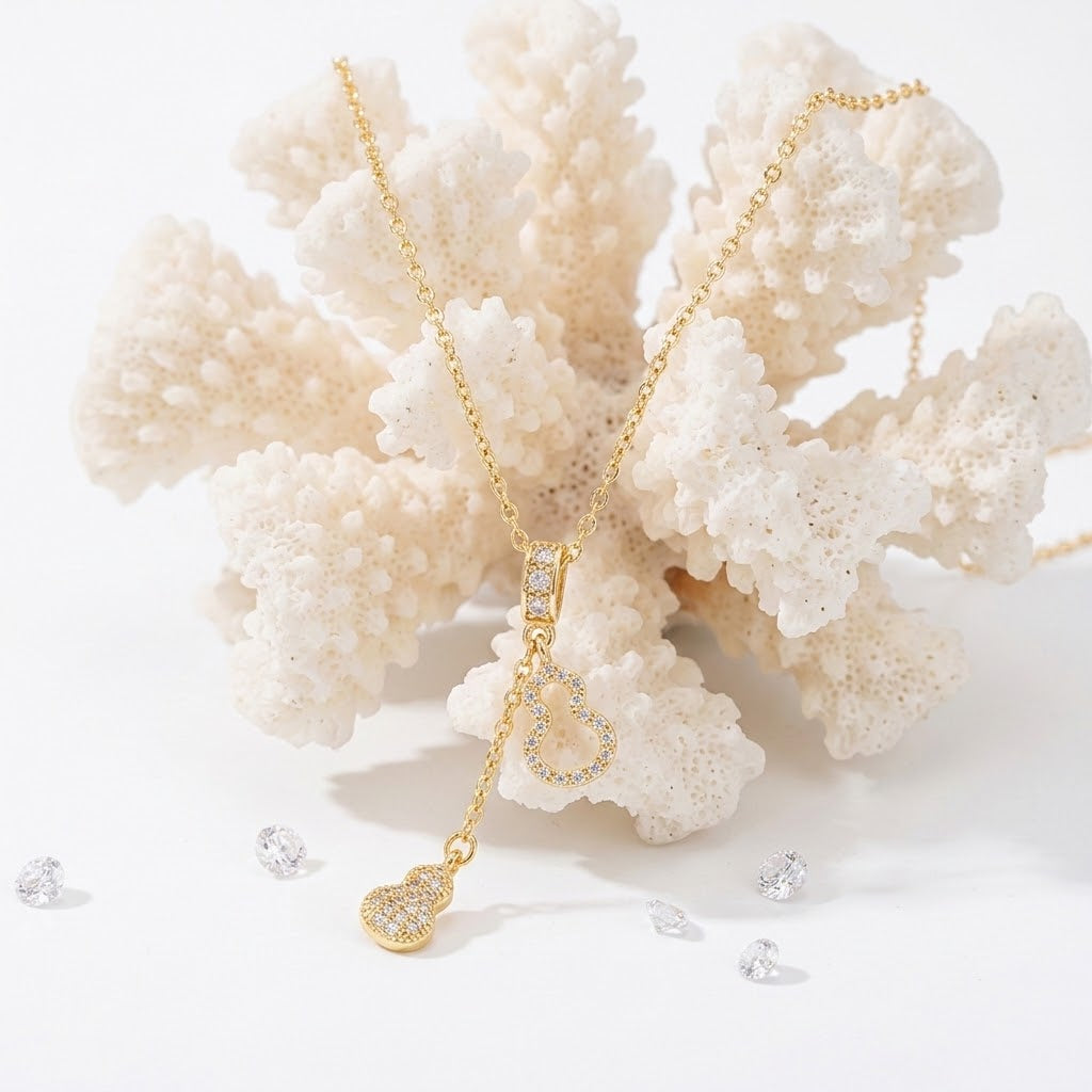 Gold-tone heart charm necklace with a teardrop center pendant and two small heart charms