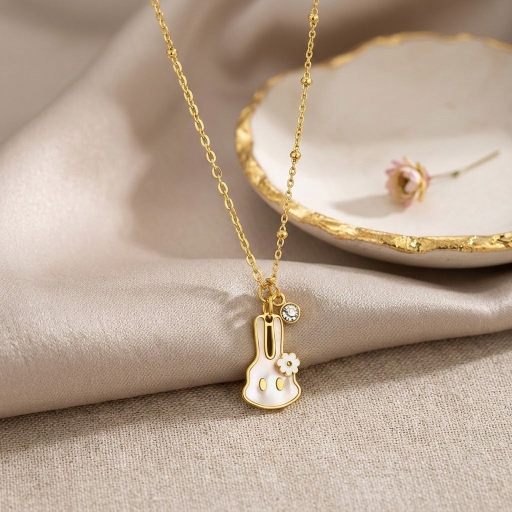 Gold-tone bunny charm necklace with flower detail and round rhinestone center