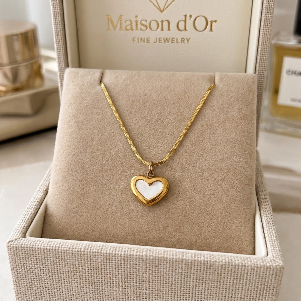 Gold-tone small heart pendant necklace displayed on a jewelry cushion