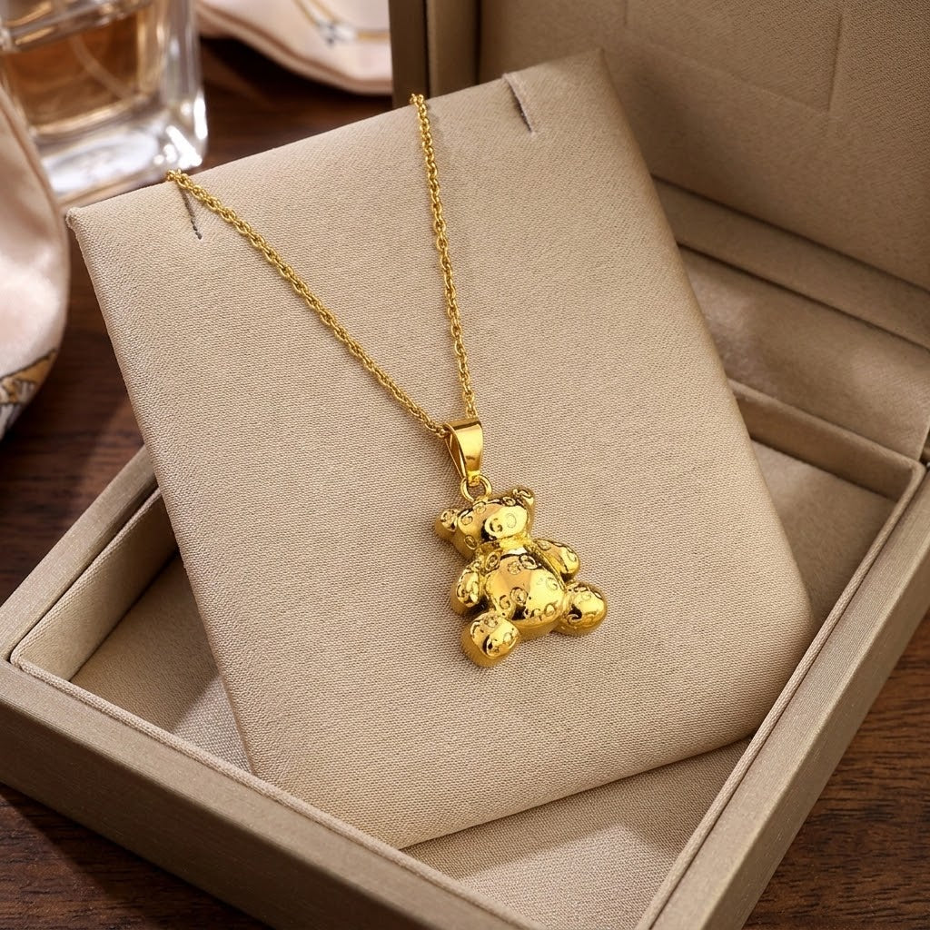 Gold bear pendant necklace resting on beige jewelry insert with chain