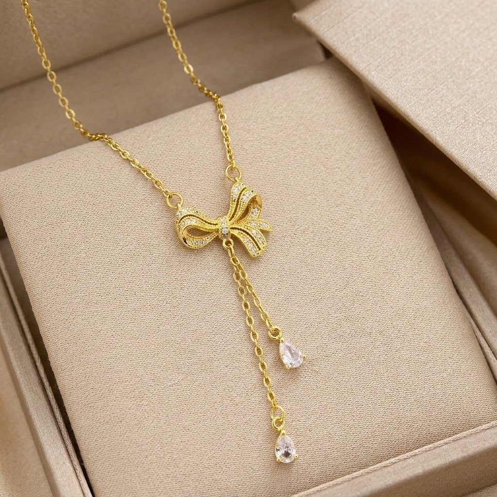 Gold bow charm necklace with teardrop crystal pendants and delicate chain
