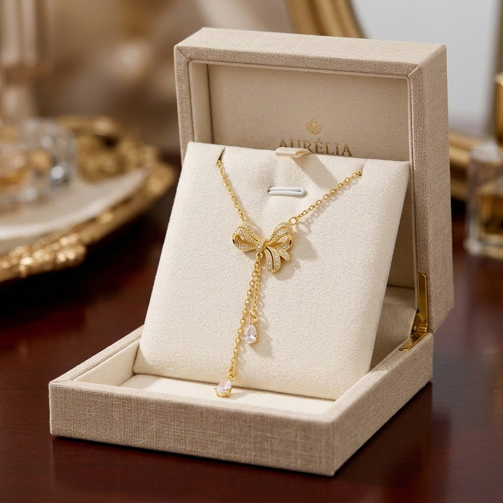 Gold bow charm necklace with two teardrop crystal pendants on chain, in gift box